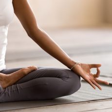 Yogi black woman practicing yoga lesson, breathing, meditating, doing Ardha Padmasana exercise, Half Lotus pose with mudra gesture, working out, indoor close up. Well being, wellness concept